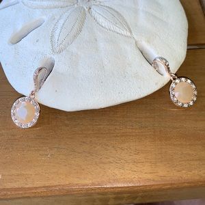 Peach colored earrings surrounded by crystals.
